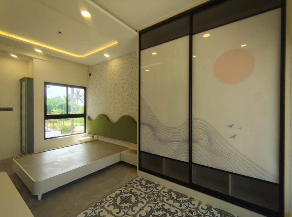 Nature-themed bedroom with scenic sliding wardrobe, black framed glass panels, flowing hill line artwork, peach sun motif, bird accents, green wave headboard, patterned flooring, and warm ceiling lighting.