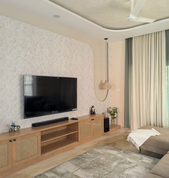Modern living room with marble TV wall, wooden media console, beige sofa, full-height curtains, and neutral decor.