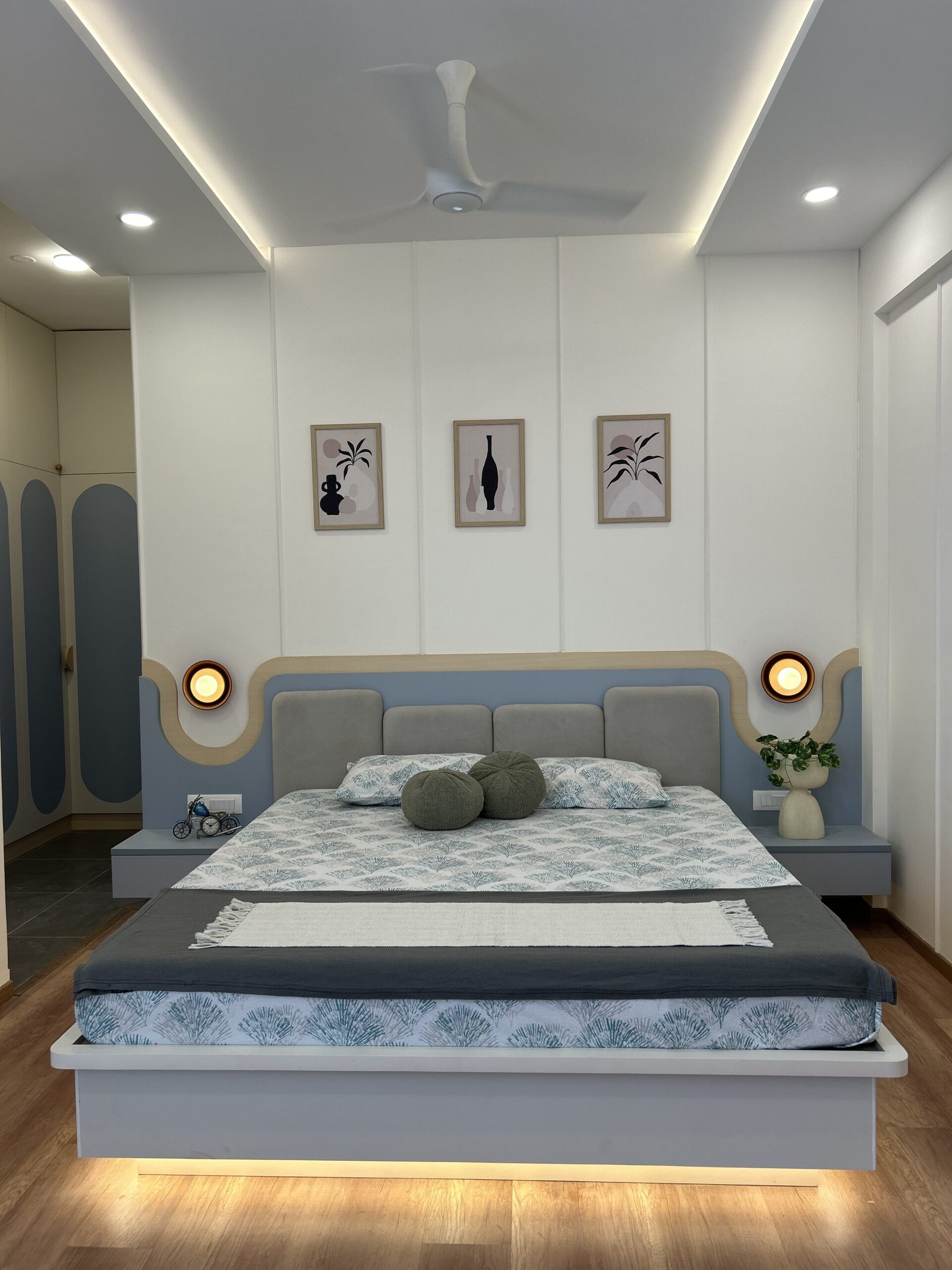 Completed-project master bedroom with curved upholstered headboard, integrated bedside tables and layered ceiling lighting.