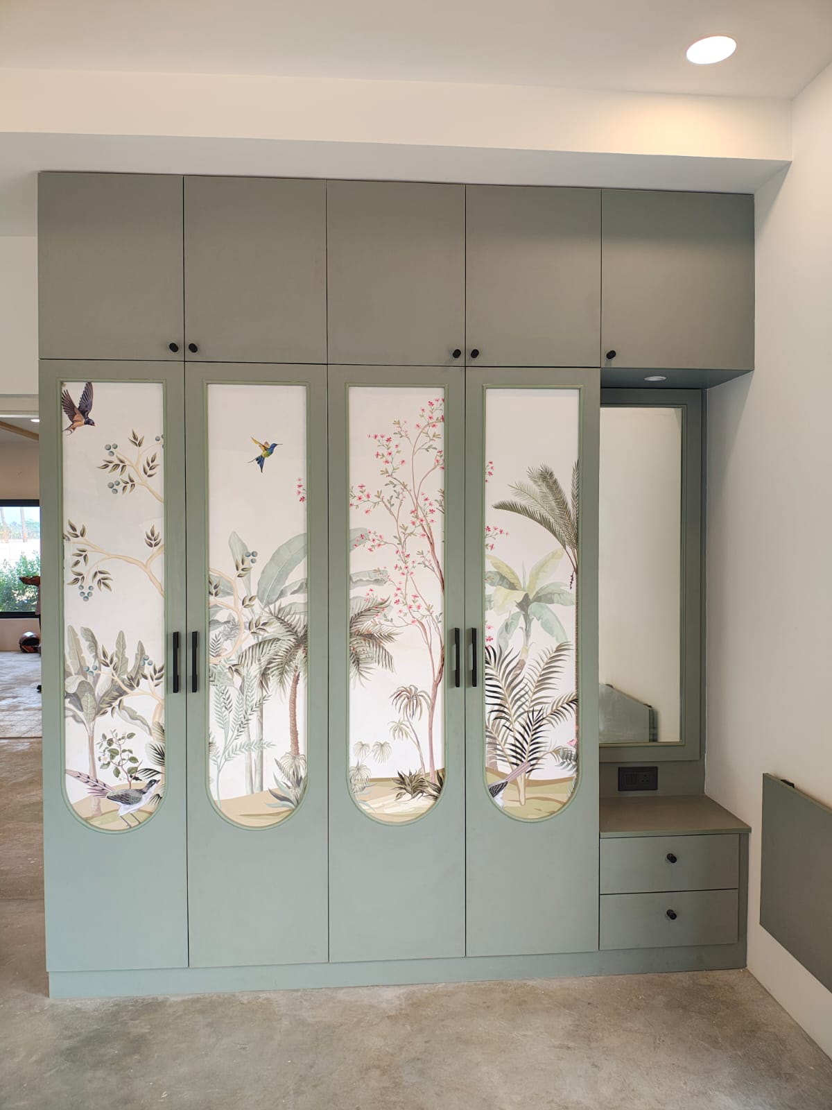 Completed-project sage green wardrobe with botanical printed shutters and an integrated dressing table.