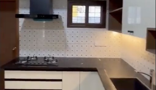 Completed Nature Vanaa villa kitchen with white cabinetry, black countertops, patterned backsplash, hob, chimney and sink